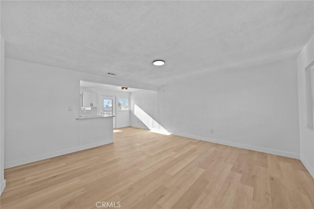 unfurnished living room with light hardwood / wood-style flooring and a textured ceiling