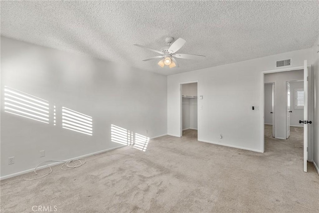 empty room with light carpet, ceiling fan, and a textured ceiling