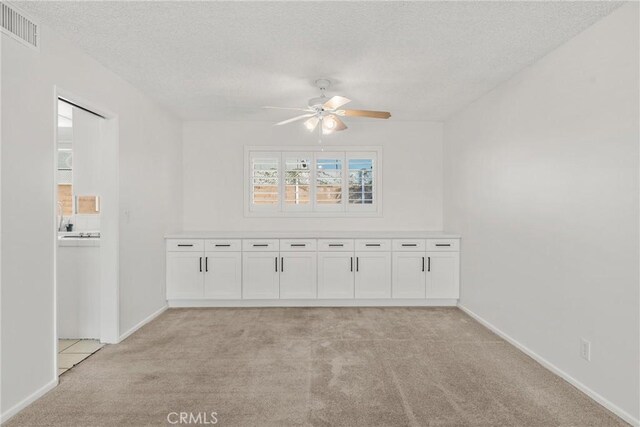 carpeted spare room featuring ceiling fan and a textured ceiling