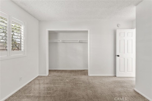 unfurnished bedroom featuring a closet, a textured ceiling, and light carpet