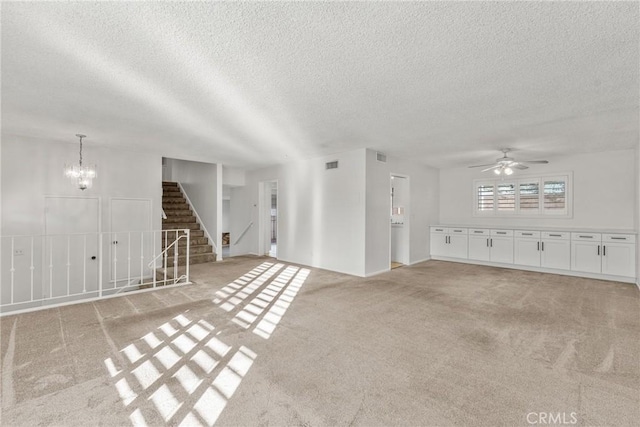 unfurnished living room featuring a textured ceiling, ceiling fan with notable chandelier, and light colored carpet