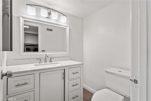 bathroom with vanity, toilet, and hardwood / wood-style flooring