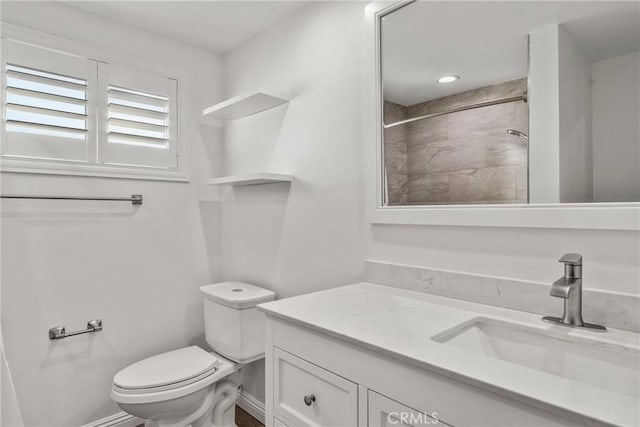 bathroom with tiled shower, vanity, and toilet