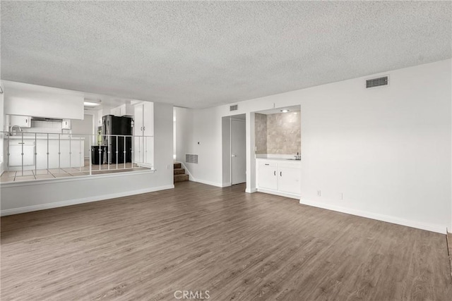 unfurnished living room featuring sink, hardwood / wood-style floors, and a textured ceiling