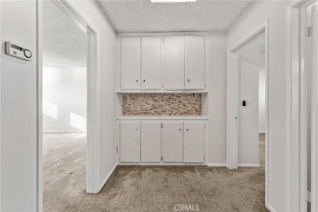 corridor with a textured ceiling and light colored carpet