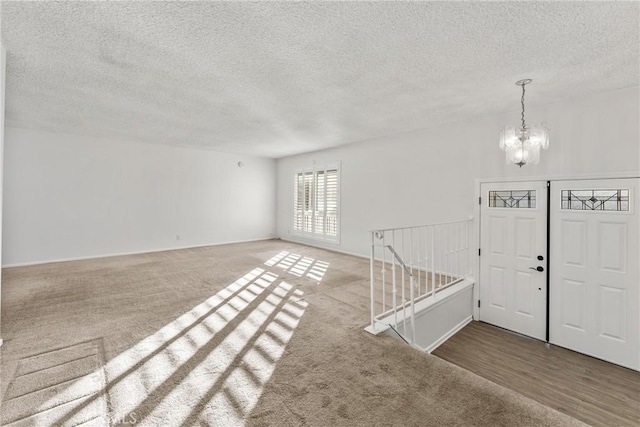 foyer entrance with a chandelier, a textured ceiling, and carpet