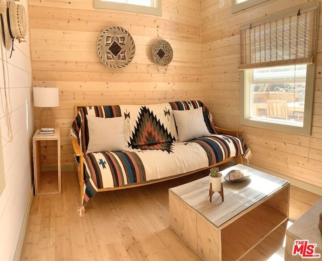 sitting room with light hardwood / wood-style floors and wood walls