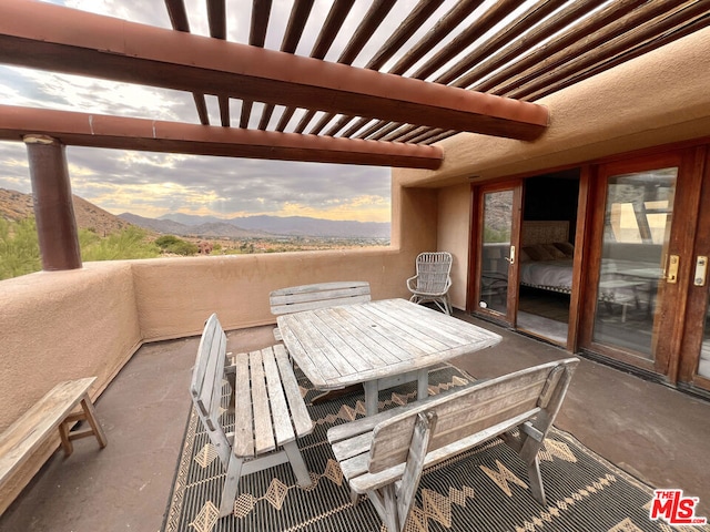 patio terrace at dusk featuring a mountain view and a balcony