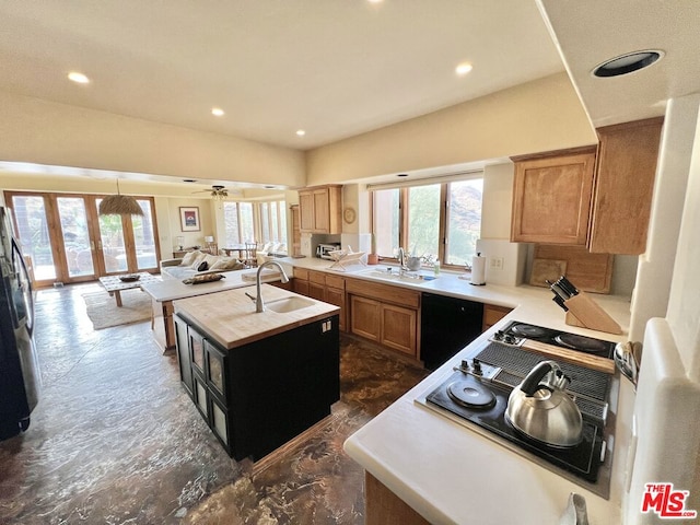 kitchen featuring dishwashing machine, a center island with sink, sink, and french doors