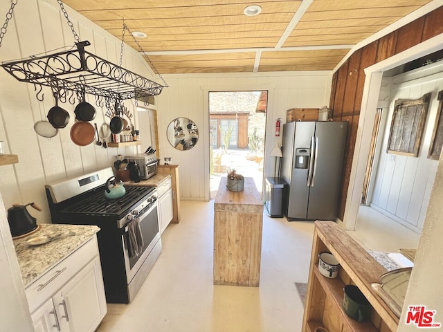 kitchen with white cabinets, wooden walls, appliances with stainless steel finishes, and wooden ceiling