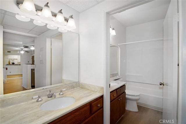 full bathroom featuring toilet, wood-type flooring,  shower combination, vanity, and ceiling fan