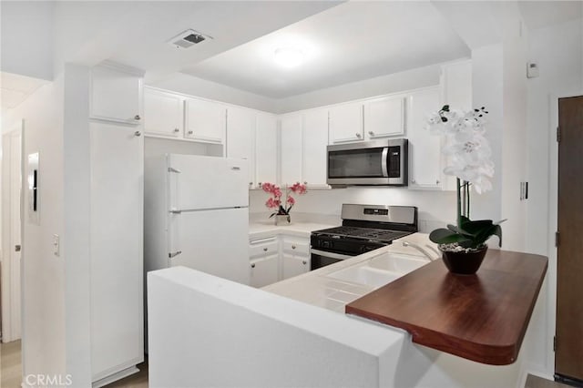 kitchen featuring sink, kitchen peninsula, white cabinets, and stainless steel appliances