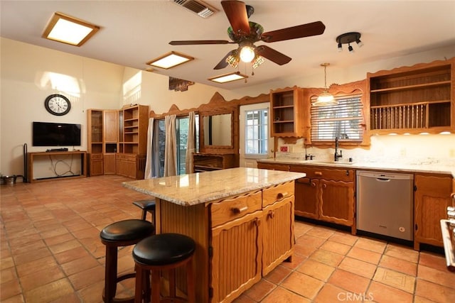 kitchen featuring a breakfast bar, sink, decorative light fixtures, a center island, and stainless steel dishwasher