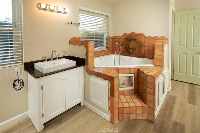 bathroom featuring hardwood / wood-style flooring, vanity, and tiled tub