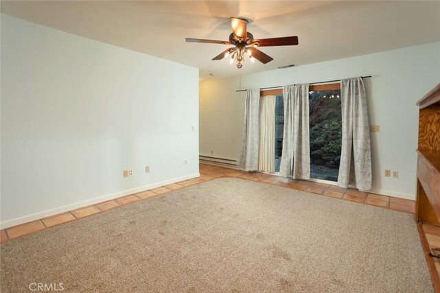 spare room featuring light tile patterned flooring, ceiling fan, and a baseboard heating unit