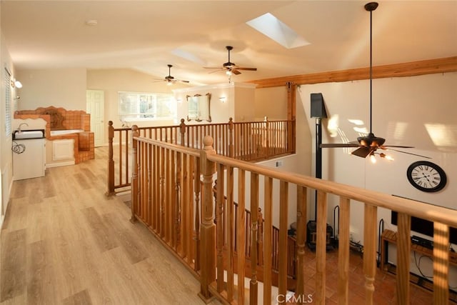 hall with light hardwood / wood-style flooring and vaulted ceiling with skylight