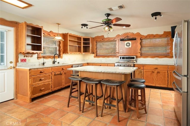 kitchen with sink, decorative light fixtures, light tile patterned floors, appliances with stainless steel finishes, and a kitchen island