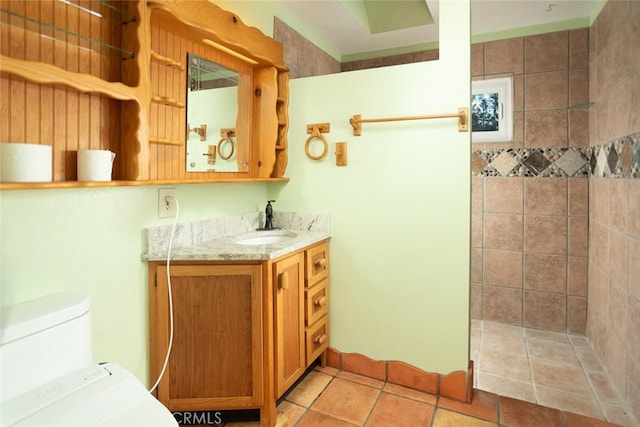 bathroom featuring tile patterned flooring, vanity, and tiled shower