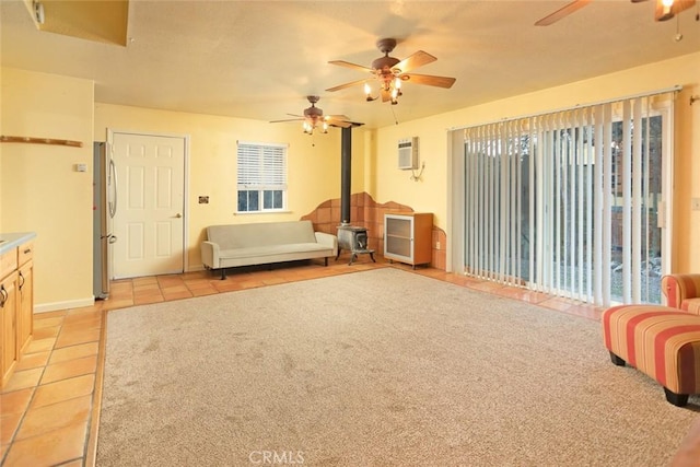 bedroom featuring a wall mounted air conditioner, stainless steel refrigerator, a wood stove, light tile patterned floors, and access to outside