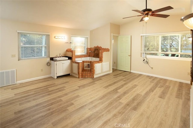 unfurnished living room featuring ceiling fan, lofted ceiling, sink, and light hardwood / wood-style floors