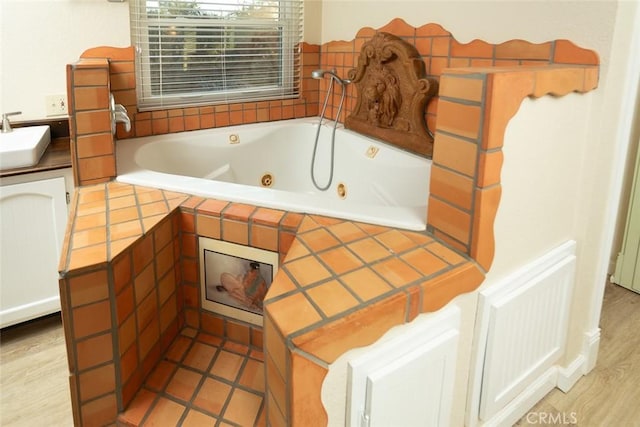 bathroom with sink and tiled tub