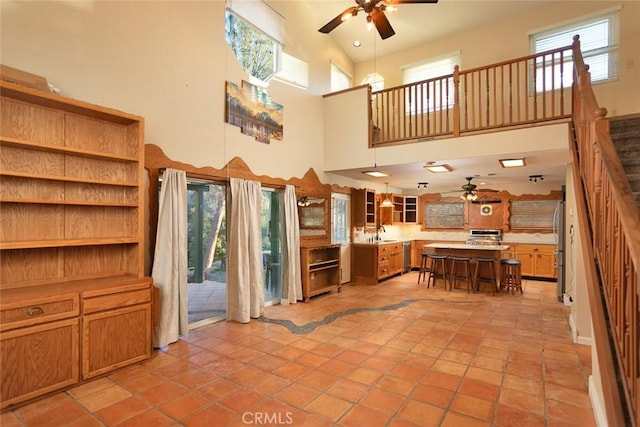 kitchen featuring a kitchen island, sink, a kitchen bar, a high ceiling, and ceiling fan