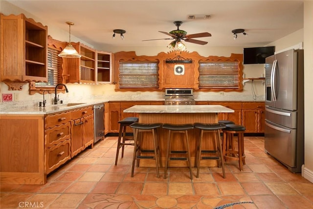 kitchen with appliances with stainless steel finishes, sink, a kitchen breakfast bar, hanging light fixtures, and a center island