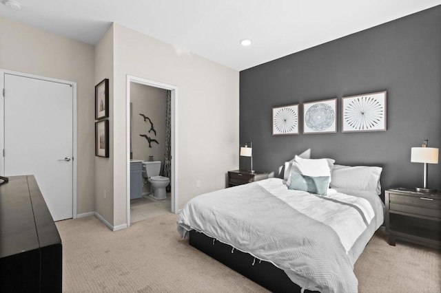 bedroom featuring light colored carpet and ensuite bathroom