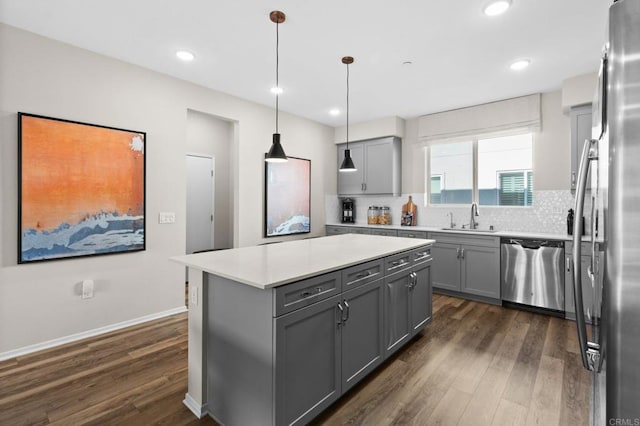 kitchen with gray cabinetry, a kitchen island, dark wood-type flooring, pendant lighting, and stainless steel appliances