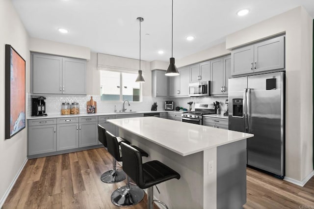 kitchen featuring a kitchen breakfast bar, decorative light fixtures, sink, a center island, and stainless steel appliances