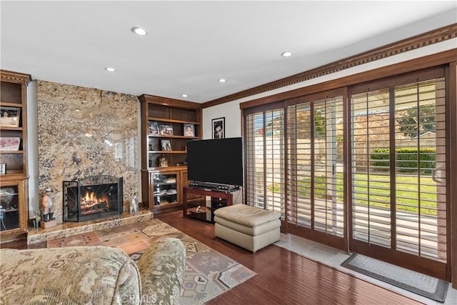 living room featuring dark wood-type flooring, a high end fireplace, built in features, and crown molding