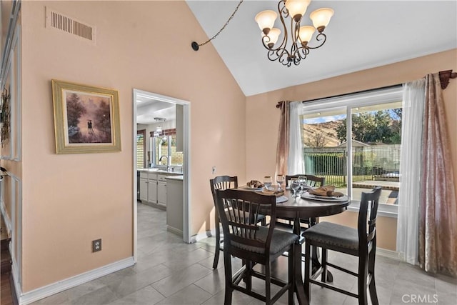 dining area with sink, light tile patterned flooring, a chandelier, and lofted ceiling