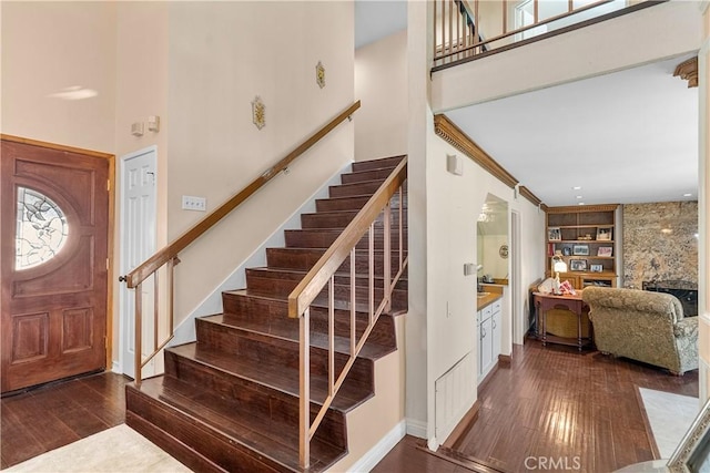 foyer featuring a towering ceiling, crown molding, dark hardwood / wood-style floors, and a fireplace