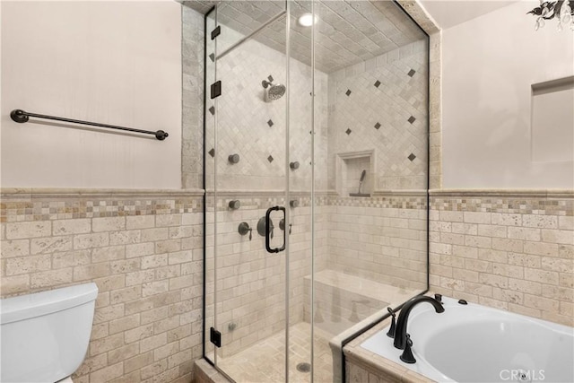 bathroom featuring toilet, tile walls, and separate shower and tub