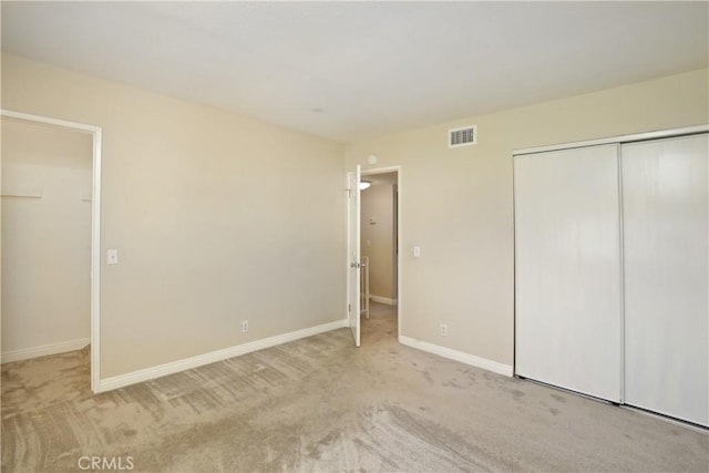 unfurnished bedroom featuring a closet and light colored carpet