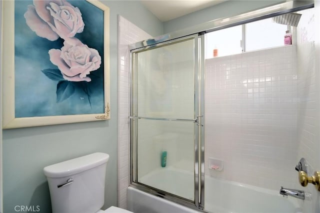 bathroom with toilet and shower / bath combination with glass door