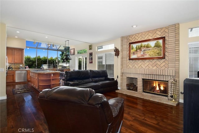 living room with a brick fireplace, plenty of natural light, and dark hardwood / wood-style flooring