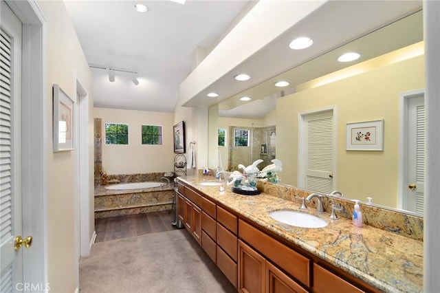 bathroom with rail lighting, separate shower and tub, lofted ceiling, and vanity