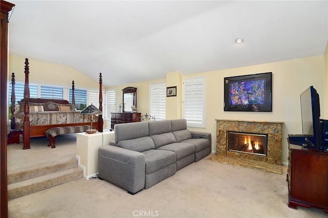 living room featuring vaulted ceiling, a fireplace, and light carpet