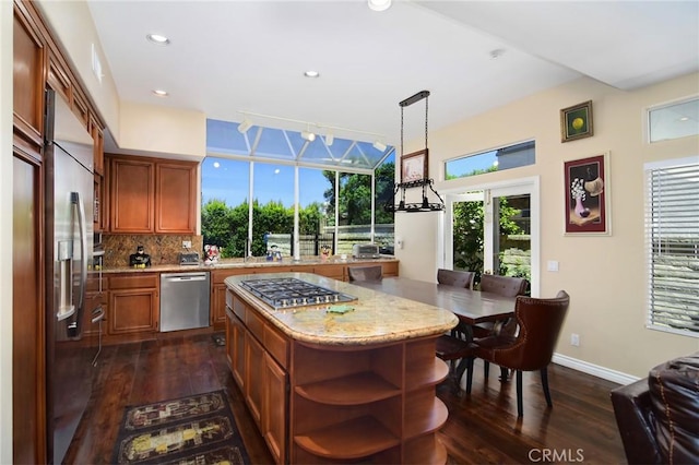 kitchen featuring a center island, decorative light fixtures, dark hardwood / wood-style flooring, stainless steel appliances, and backsplash