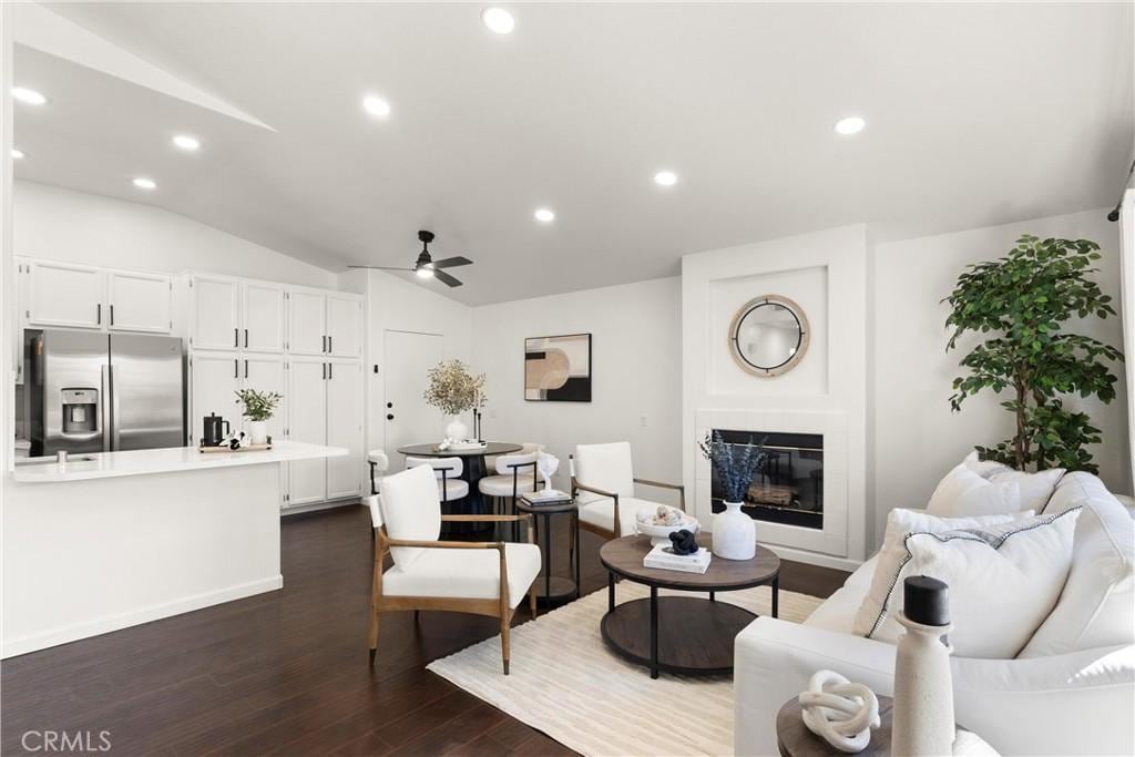 living room featuring lofted ceiling, dark hardwood / wood-style flooring, a high end fireplace, and ceiling fan