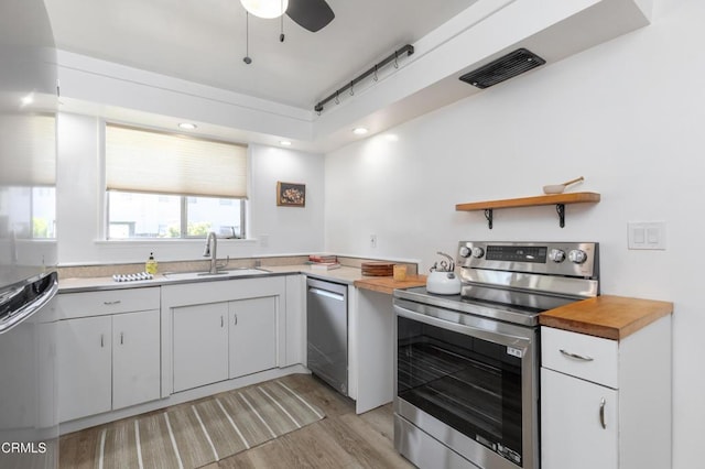 kitchen with ceiling fan, light hardwood / wood-style floors, wooden counters, sink, and stainless steel appliances