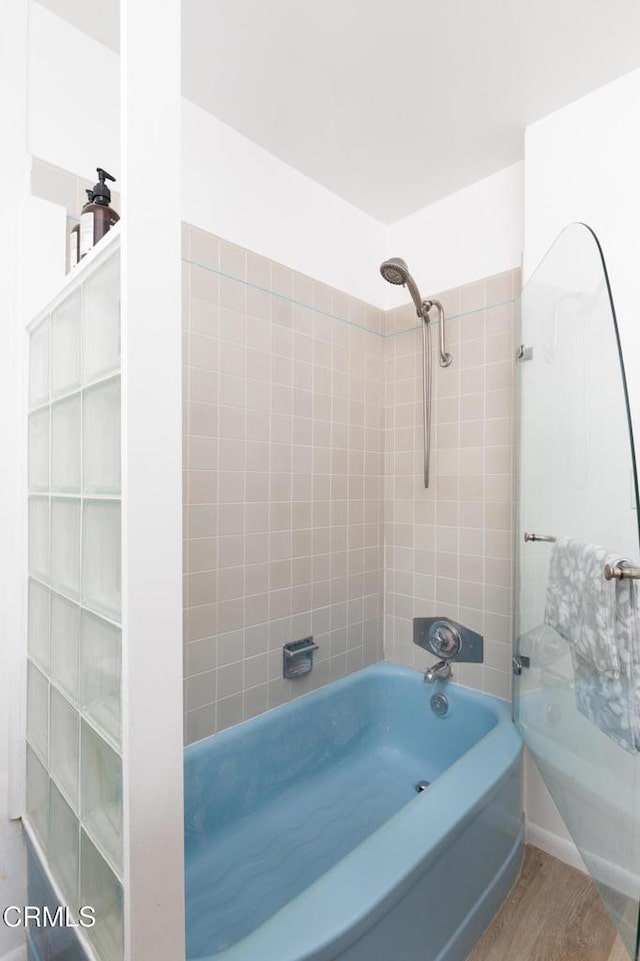 bathroom featuring wood-type flooring and tiled shower / bath