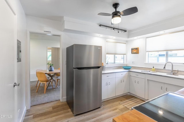 kitchen featuring sink, white cabinetry, stainless steel refrigerator, and light hardwood / wood-style floors