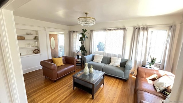 living room with hardwood / wood-style floors, plenty of natural light, a chandelier, and built in features