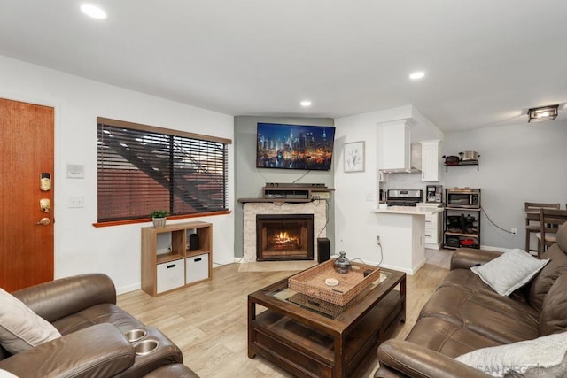 living room featuring light hardwood / wood-style flooring and a stone fireplace