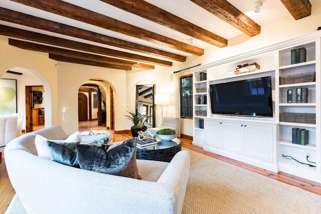 living room featuring beamed ceiling and light hardwood / wood-style floors