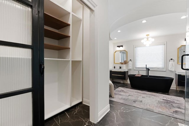 bathroom featuring vanity, a bath, and a notable chandelier