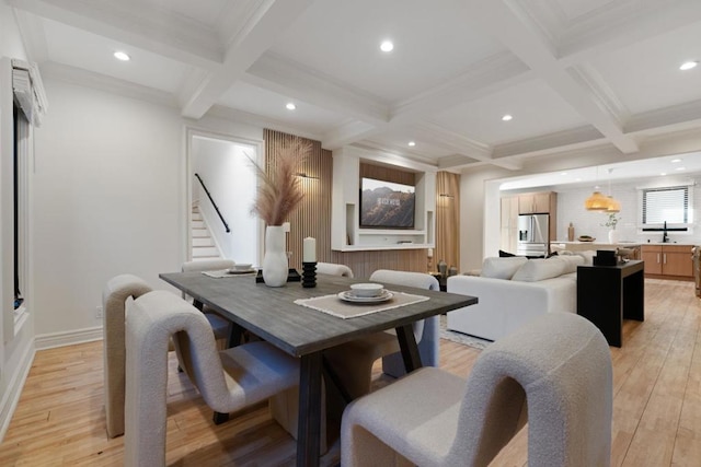 dining room with coffered ceiling, beam ceiling, ornamental molding, and light hardwood / wood-style floors