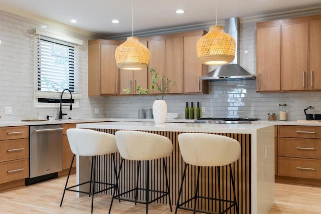 kitchen with tasteful backsplash, wall chimney range hood, hanging light fixtures, and stainless steel gas stovetop